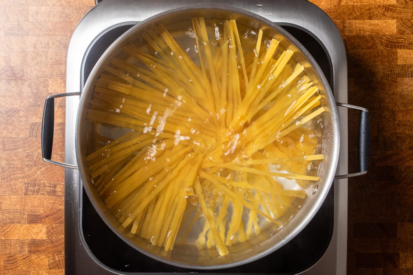 fettuccine noodles cooking in a pot.