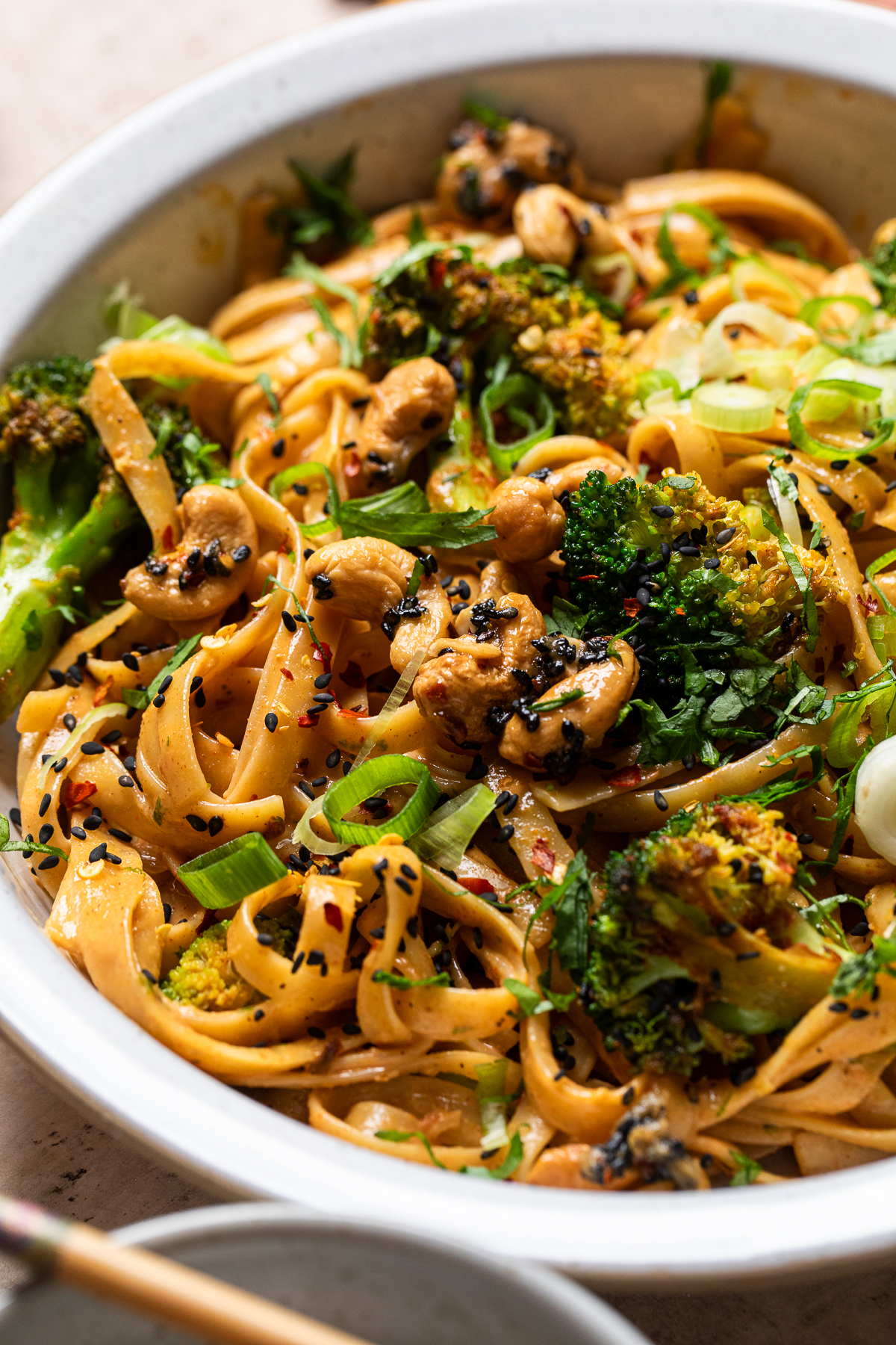 close up of smokey chili lime tahini broccoli noodles in a white bowl.