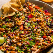 a large bowl of southwest dense bean salad with tortilla chips on the side.