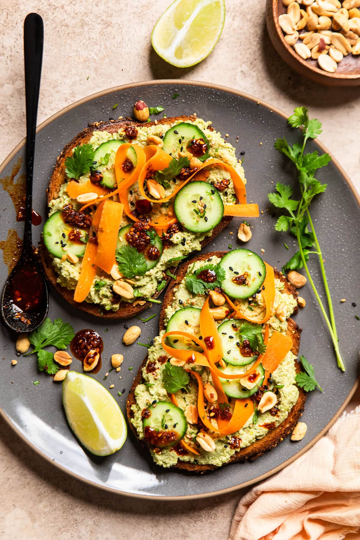 two slices of edamame toast with carrot ribbons, sliced baby cucumbers and chili crunch.