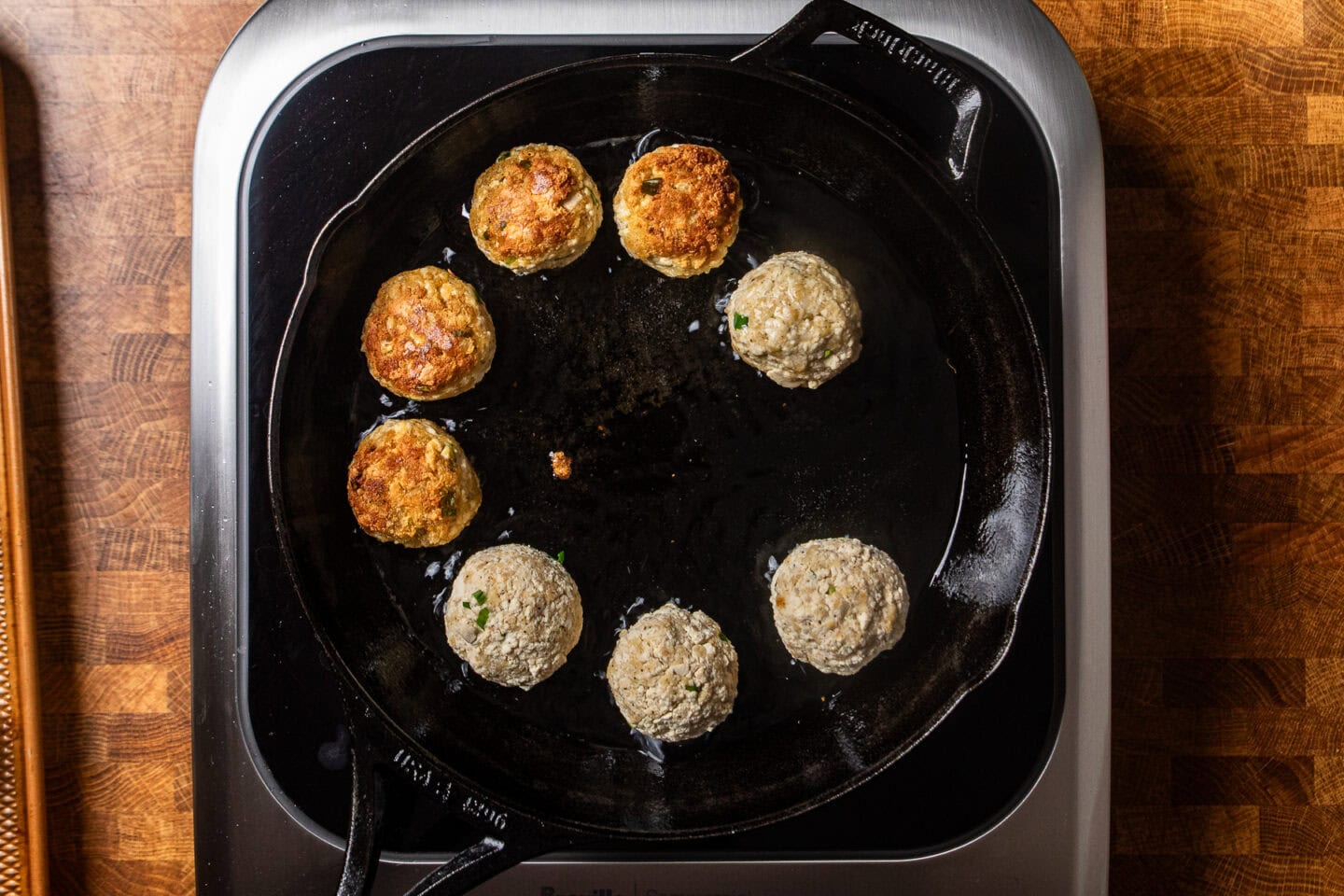 tofu meatballs cooking in a cast iron skillet.