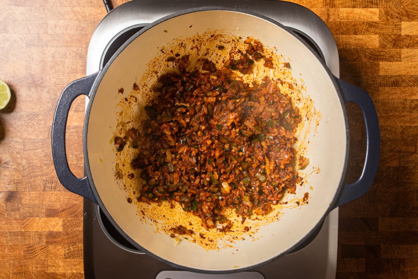 spices, onions, and peppers cooking in a dutch oven.
