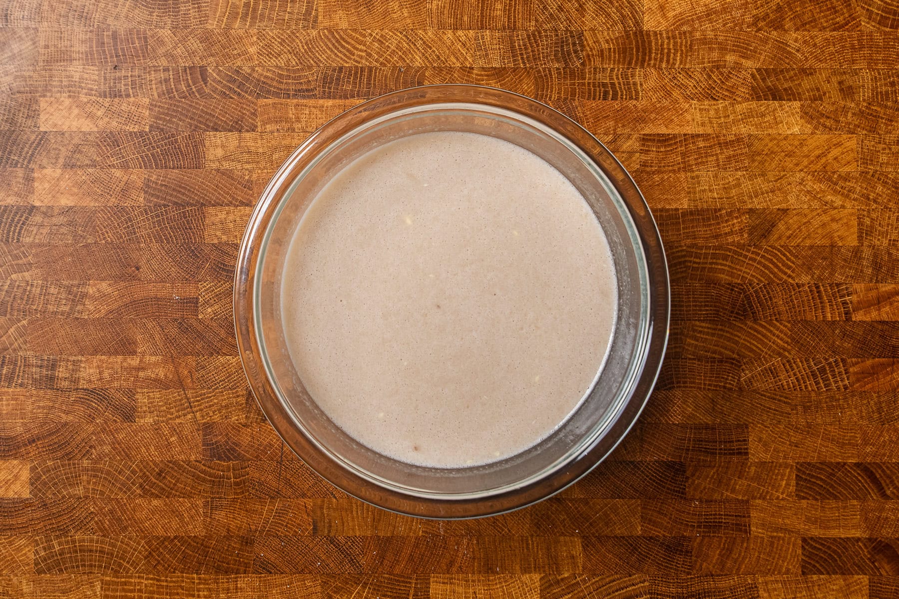 wet and dry ingredients for baked oatmeal mixed together in a large glass bowl.