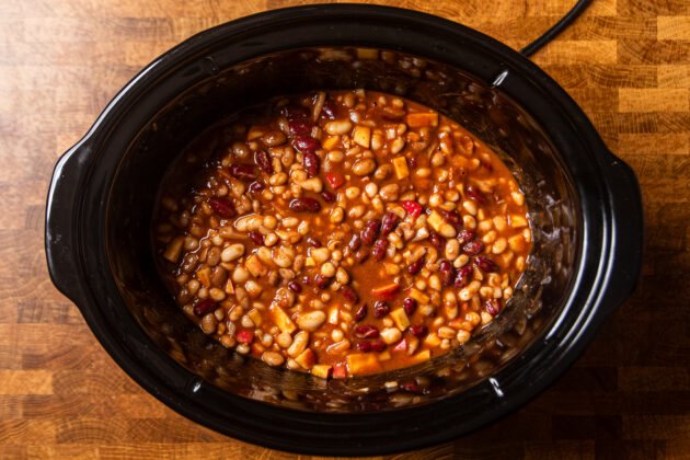 ingredients to make apple cider baked beans in a slow cooker cooking.