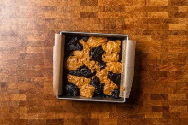 uncooked and unswirled pumpkin brownie batters in a baking dish.