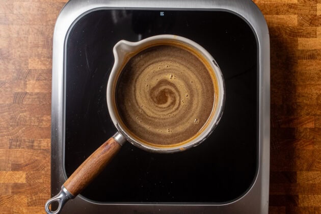 toffee sauce cooking in a small pot on a burner.